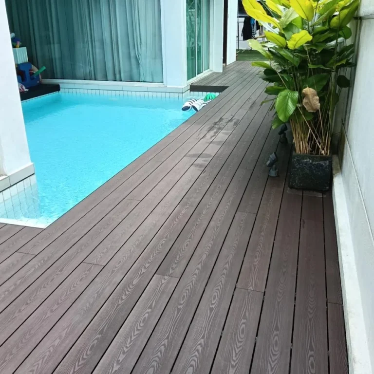 View of a modern swimming pool featuring light grey WPC decking floor with a gardener installing fresh lawn.