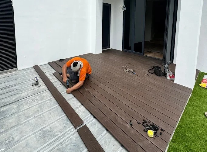 Handyman performing outdoor decking installation on a residential patio