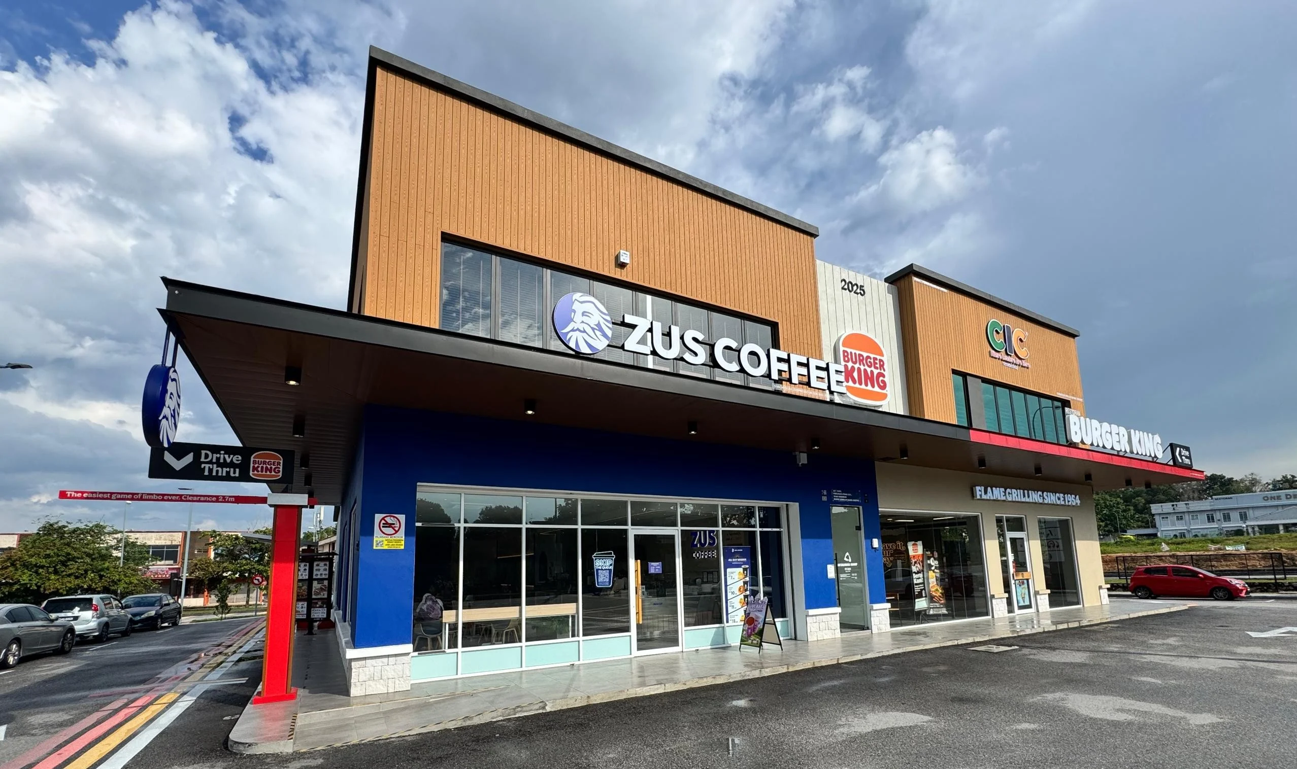 Composite wood wall cladding installed on a commercial building exterior with ZUS Coffee and Burger King storefronts